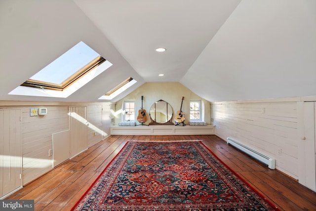 bonus room featuring a baseboard heating unit, vaulted ceiling with skylight, wood-type flooring, and wood walls