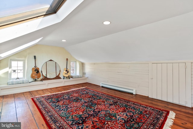 bonus room featuring a wealth of natural light, vaulted ceiling with skylight, baseboard heating, and hardwood / wood-style flooring