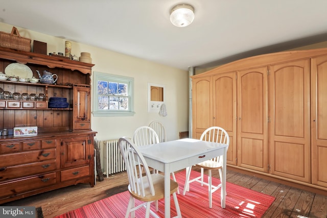 dining area with hardwood / wood-style floors and radiator heating unit