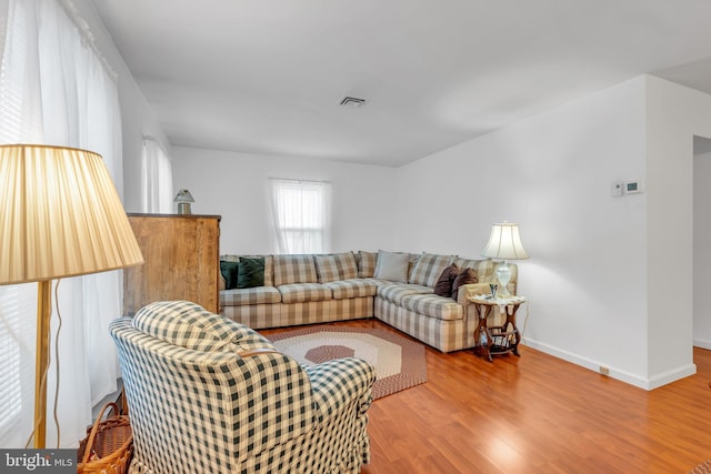 living area featuring baseboards, visible vents, and wood finished floors