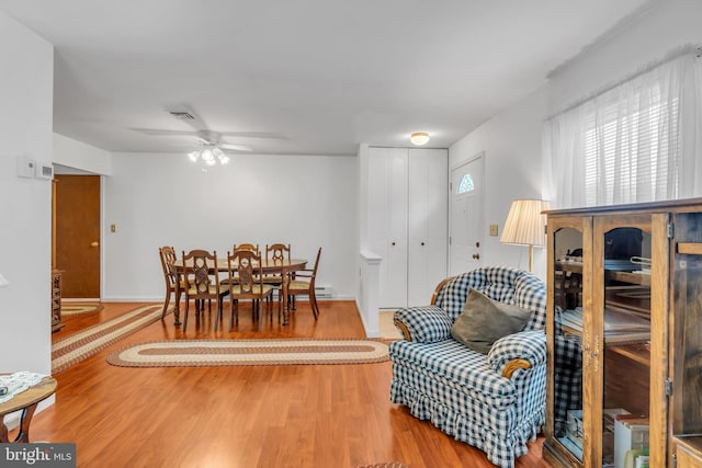 dining space with a ceiling fan, visible vents, baseboards, and wood finished floors