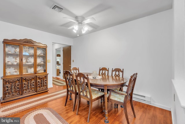 dining area featuring a baseboard radiator, wood finished floors, visible vents, baseboards, and a ceiling fan