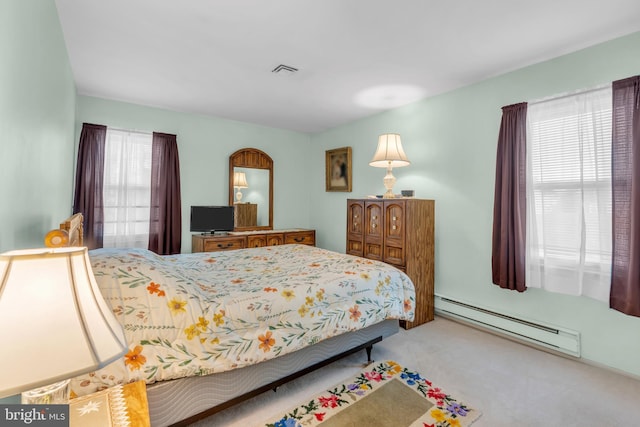 bedroom with visible vents, a baseboard heating unit, and light colored carpet