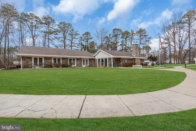 view of front facade featuring stone siding, a chimney, and a front yard