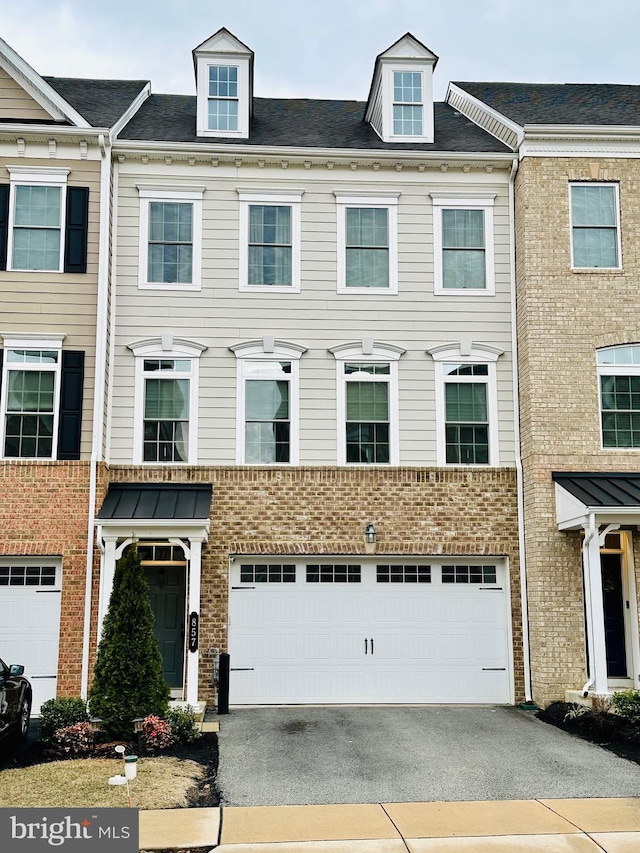 townhome / multi-family property featuring aphalt driveway, an attached garage, and brick siding