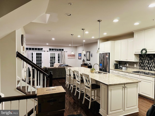 kitchen featuring dark wood finished floors, appliances with stainless steel finishes, open floor plan, a sink, and recessed lighting