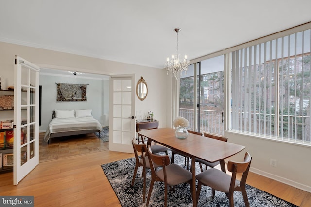 dining area featuring ornamental molding, baseboards, a notable chandelier, light wood-style floors, and french doors