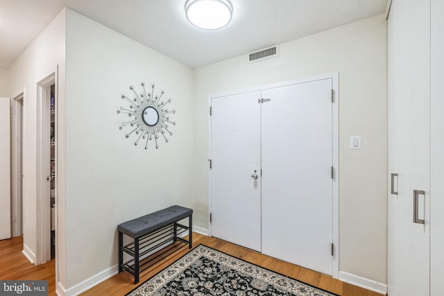 foyer entrance featuring visible vents, baseboards, and light wood-type flooring