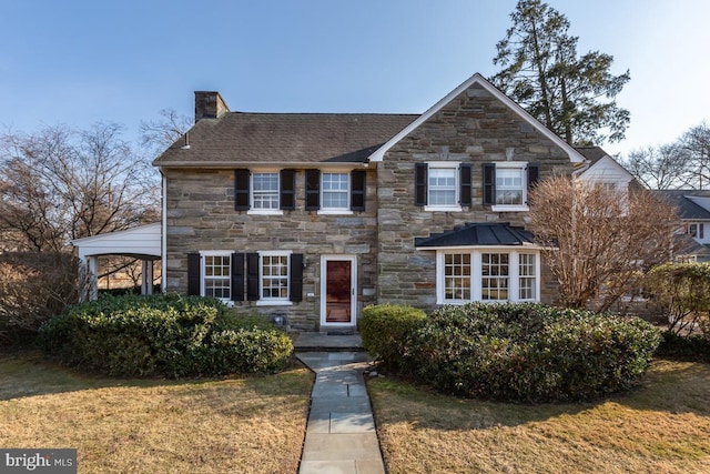 view of front of property with stone siding, a chimney, and a front lawn