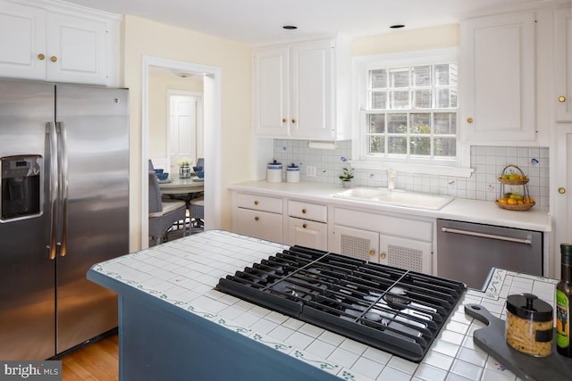 kitchen with appliances with stainless steel finishes, backsplash, a sink, and white cabinetry