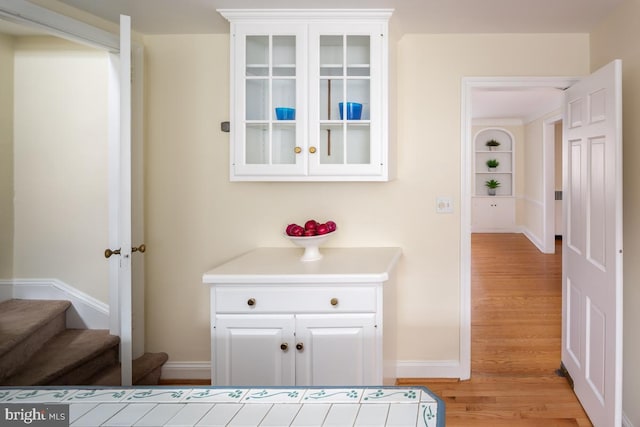 interior space featuring baseboards, stairway, and light wood finished floors