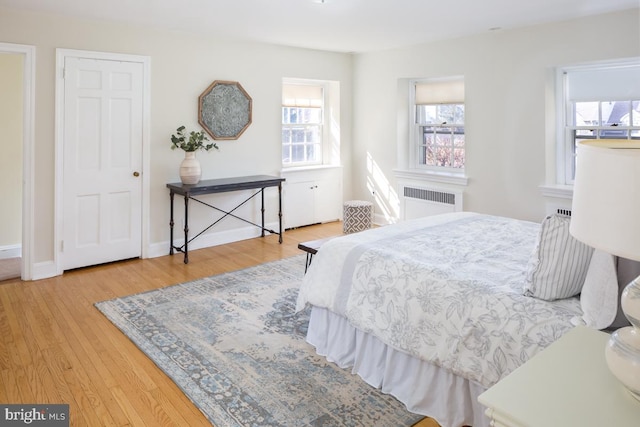 bedroom featuring radiator heating unit, wood finished floors, and baseboards