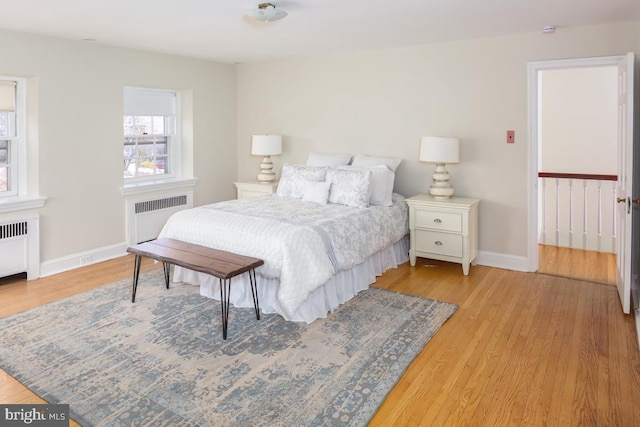 bedroom with radiator heating unit, baseboards, and wood finished floors