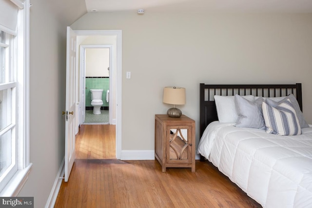 bedroom featuring multiple windows, baseboards, and wood finished floors