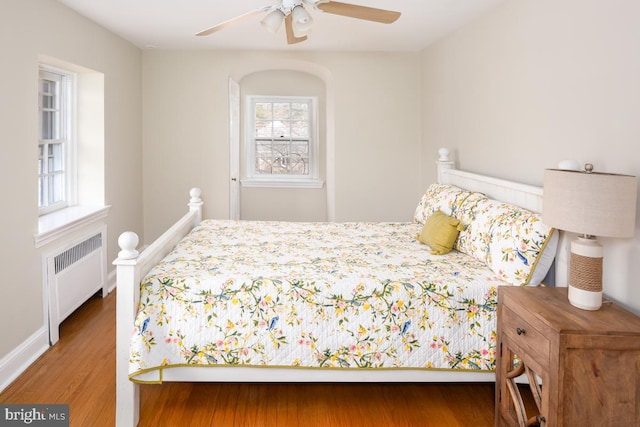 bedroom featuring baseboards, radiator heating unit, and wood finished floors