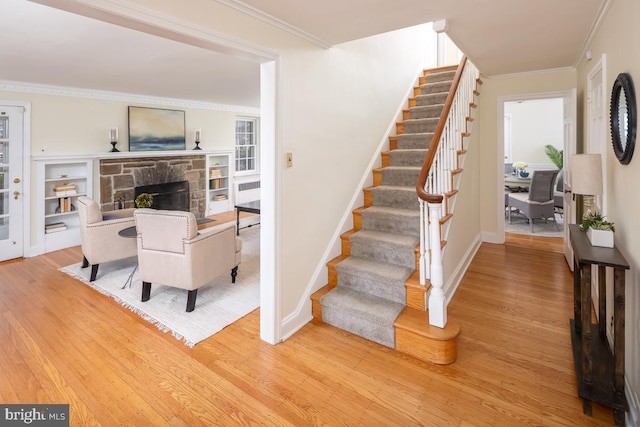 staircase with ornamental molding, a fireplace, wood finished floors, and baseboards