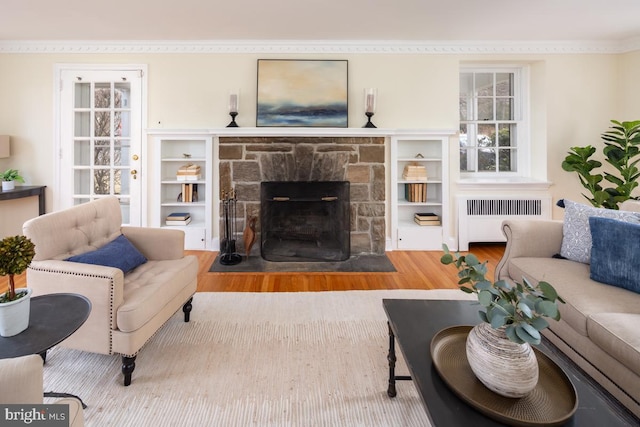 living area featuring a fireplace, radiator heating unit, and wood finished floors