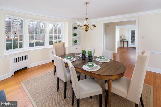 dining room with baseboards, radiator, light wood-style flooring, ornamental molding, and a chandelier