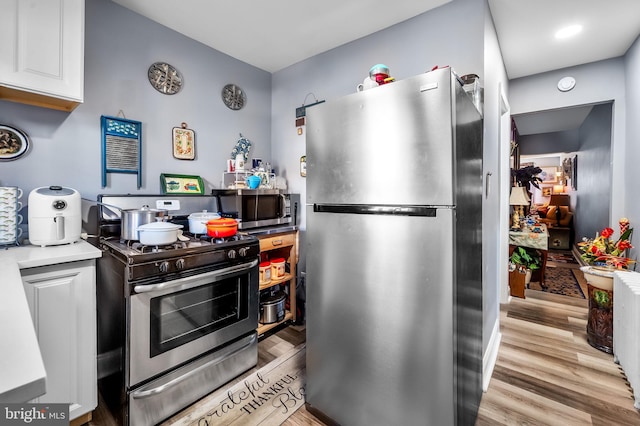 kitchen with light hardwood / wood-style flooring, stainless steel appliances, and white cabinets