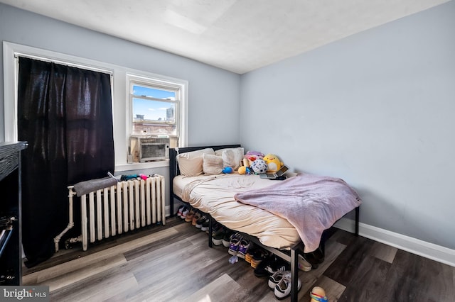 bedroom with radiator, cooling unit, and wood-type flooring