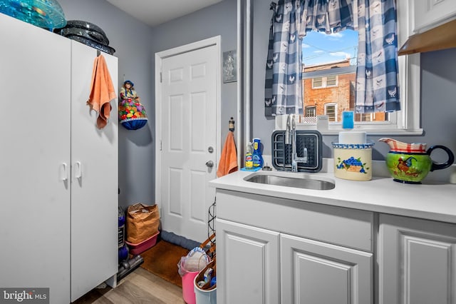 kitchen featuring sink, white cabinetry, and wood-type flooring