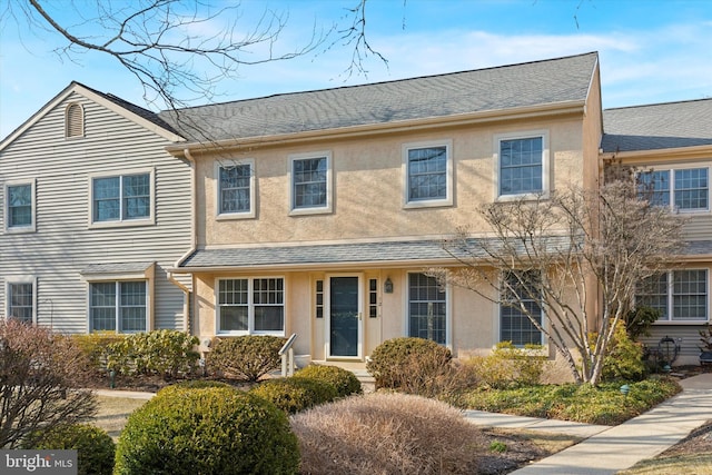 townhome / multi-family property featuring roof with shingles and stucco siding