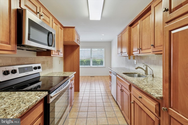 kitchen featuring appliances with stainless steel finishes, brown cabinetry, a sink, and light tile patterned floors