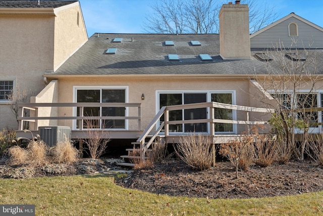 back of house featuring stucco siding, a chimney, central AC, and roof with shingles