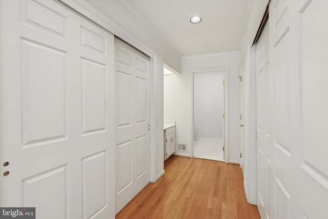 corridor with recessed lighting, visible vents, baseboards, ornamental molding, and light wood-type flooring