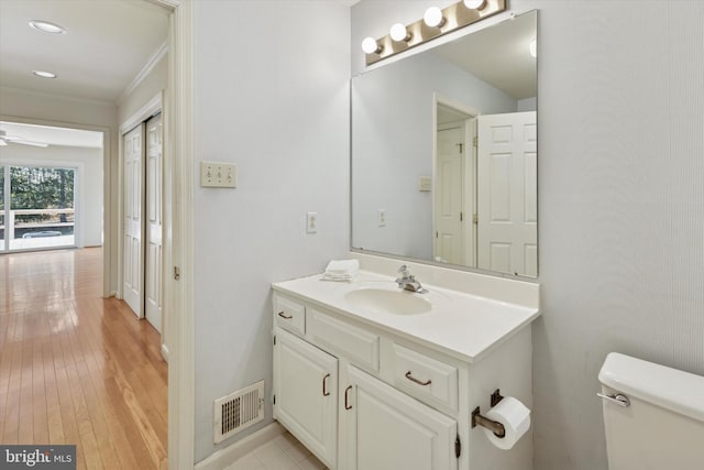 bathroom featuring visible vents, a ceiling fan, toilet, wood finished floors, and vanity