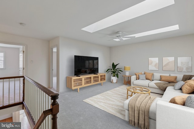 living area with a ceiling fan, a skylight, and carpet