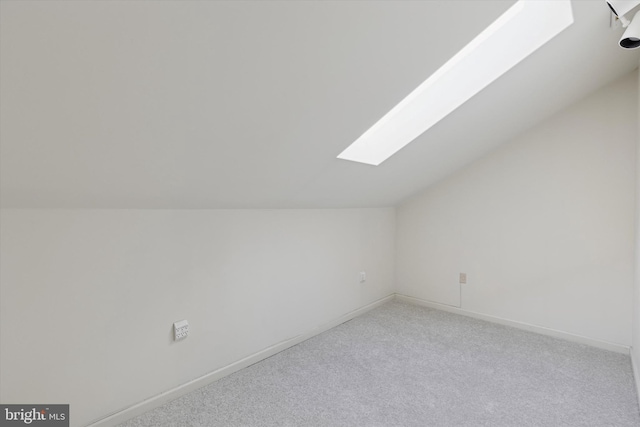 additional living space with light carpet, lofted ceiling with skylight, and baseboards