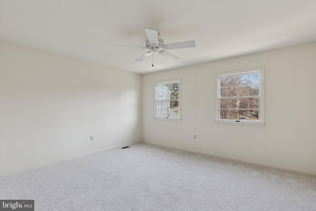 carpeted empty room with visible vents, ceiling fan, and baseboards