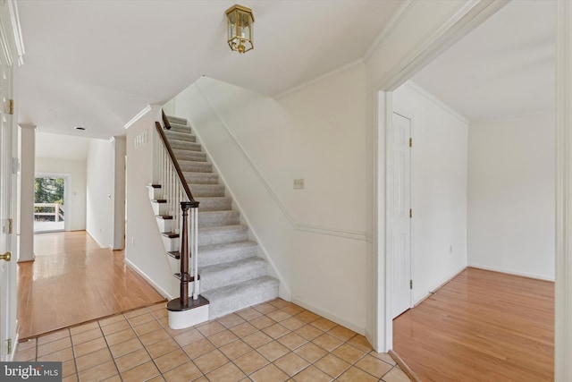 stairway featuring ornamental molding and wood finished floors