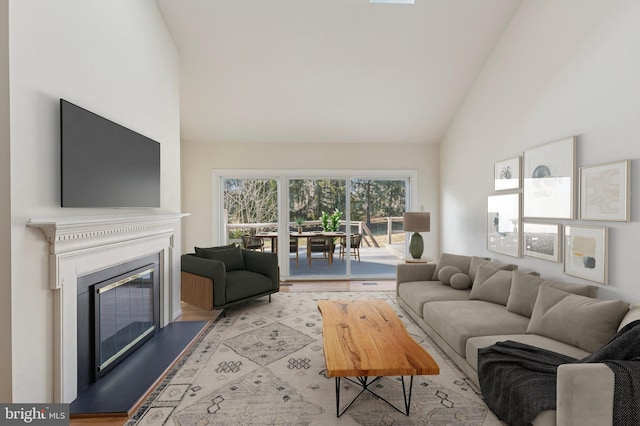 living room with high vaulted ceiling, wood finished floors, and a glass covered fireplace