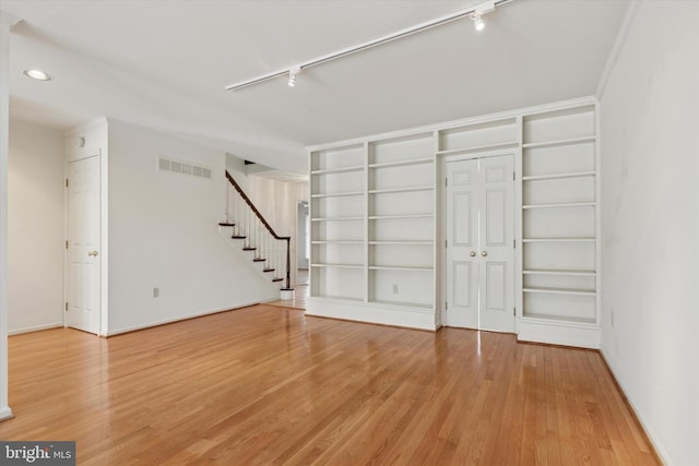 interior space with built in shelves, wood finished floors, visible vents, stairway, and track lighting