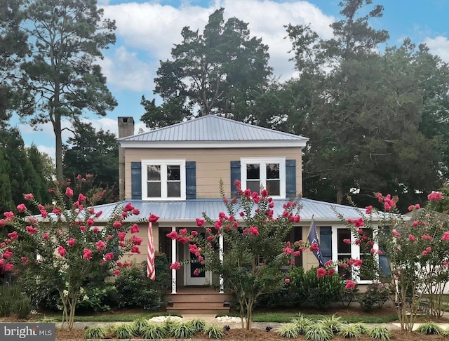 view of front of house featuring metal roof and a chimney