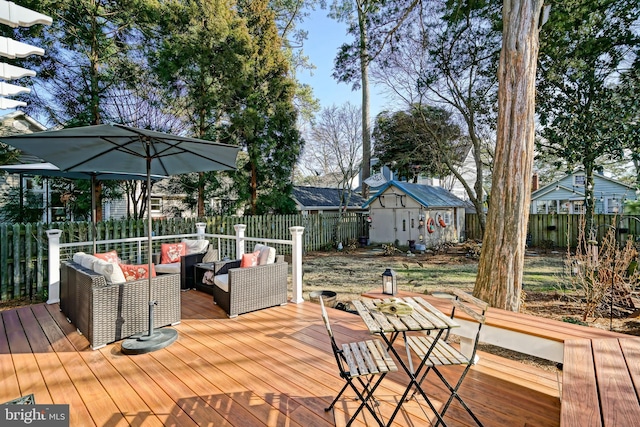 wooden deck featuring outdoor lounge area, an outdoor structure, a fenced backyard, and a shed