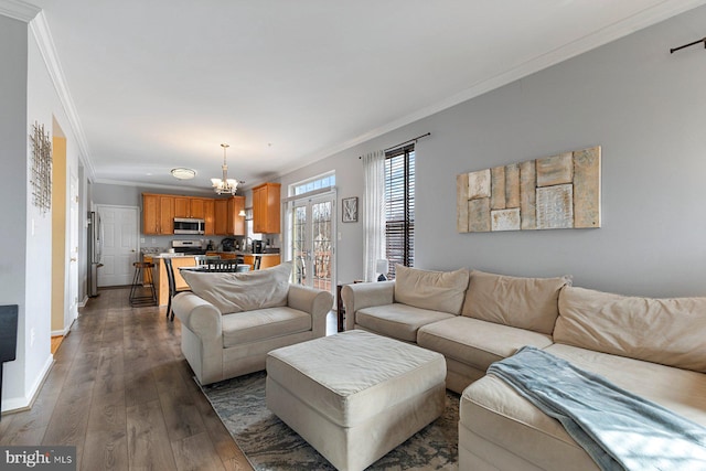 living area with dark wood-style floors, ornamental molding, an inviting chandelier, and baseboards