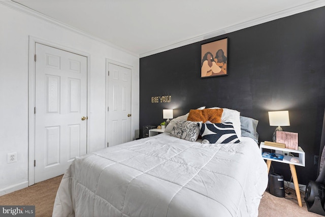 carpeted bedroom with an accent wall, ornamental molding, and baseboards