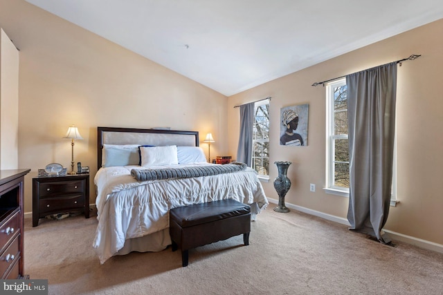 bedroom with vaulted ceiling, baseboards, and light colored carpet