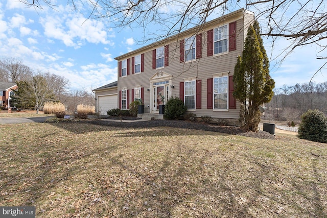 colonial home featuring an attached garage, cooling unit, and a front yard