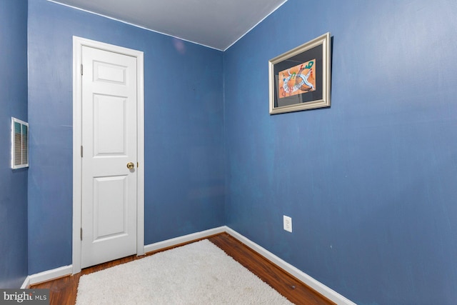 unfurnished room featuring dark wood-type flooring, visible vents, and baseboards