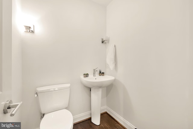 half bathroom with a sink, wood finished floors, toilet, and baseboards