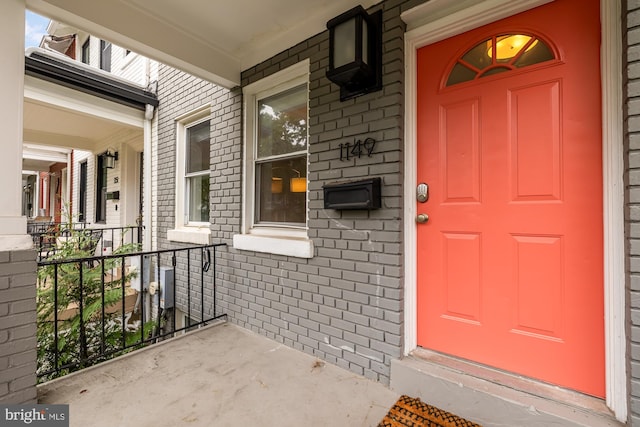 entrance to property with brick siding and a porch