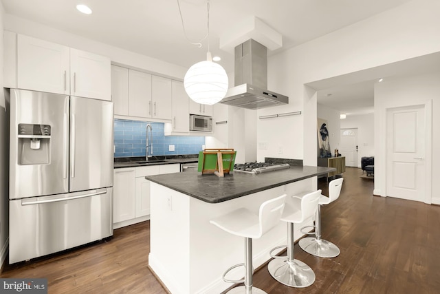 kitchen with island range hood, dark countertops, stainless steel appliances, white cabinetry, and a sink