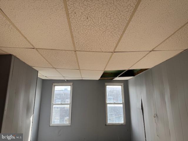 spare room featuring a paneled ceiling and wooden walls