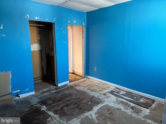 unfurnished bedroom with a paneled ceiling and baseboards