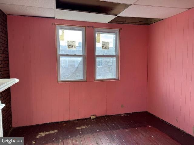 empty room featuring dark wood finished floors and a drop ceiling