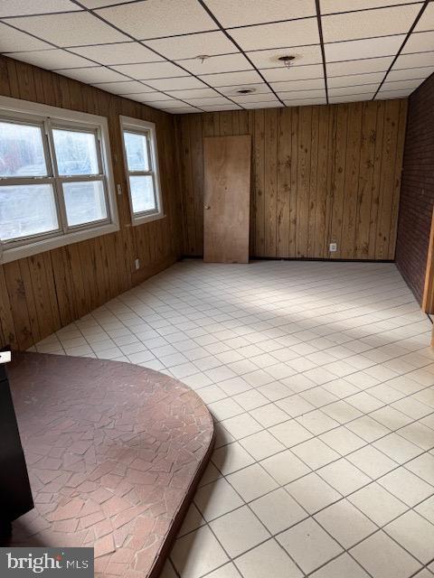 spare room featuring wooden walls and a drop ceiling